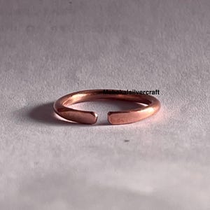 Peut inclure: Une simple bague en cuivre avec un espace sur un côté. La bague est lisse et a une forme légèrement arrondie.