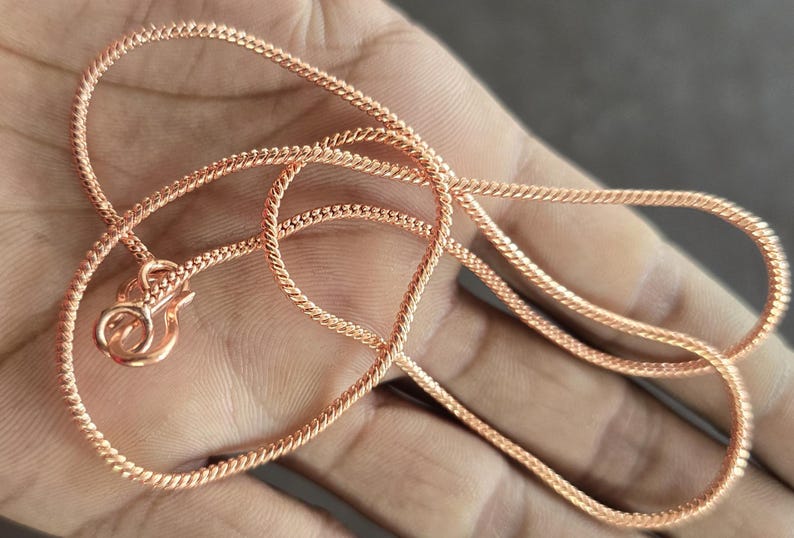 Puede incluir: Un collar de cadena de oro rosa con un dise&ntilde;o delicado y trenzado. La cadena est&aacute; hecha de un metal liso y brillante y tiene un cierre de langosta.
