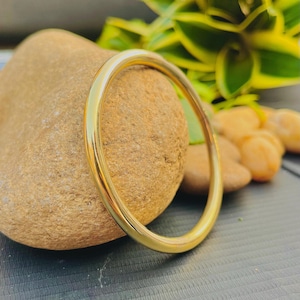 May include: A simple gold bangle bracelet, a classic and timeless piece of jewelry.