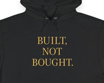 May include: Black hooded sweatshirt with the text "BUILT, NOT BOUGHT" in gold lettering. The sweatshirt has a front pocket and a drawstring hood. The Champion logo is visible on the left sleeve.