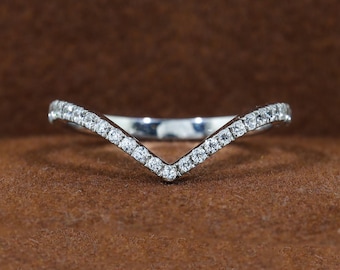 May include: A V-shaped chevron ring crafted from polished silver-toned metal, featuring a row of small, clear, round-cut stones embedded along the entire top surface of the band, creating a continuous sparkling effect across the pointed design.
