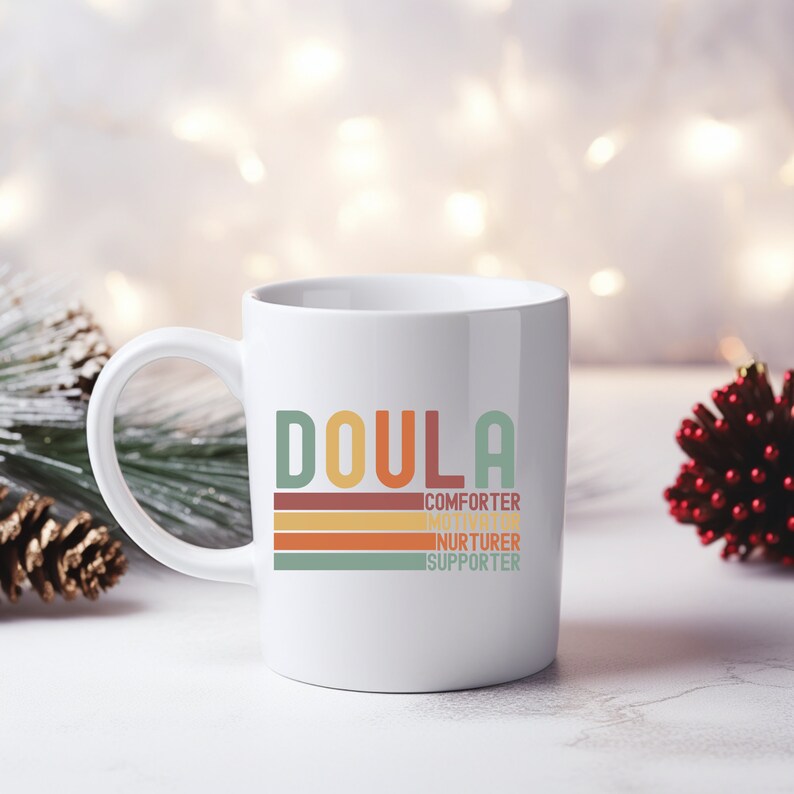 Op de afbeelding: Witte keramische mok met een kleurrijke afbeelding waarop "Doula" staat en de woorden "trooster, motivator, verzorger, supporter" in een retro-stijl staan.