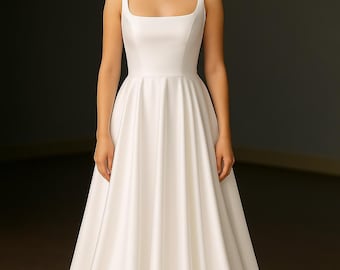 May include: A floor-length white satin gown featuring a square neckline, wide shoulder straps, and a fitted bodice that transitions into a full, pleated skirt with a slight train. The fabric has a smooth, lustrous finish throughout the garment.