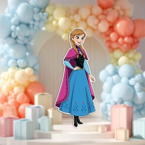 May include: A cut-out of a cartoon character, Anna from Frozen, wearing a blue dress with a pink cape. The background features a balloon arch in pastel colors and decorative gift boxes.