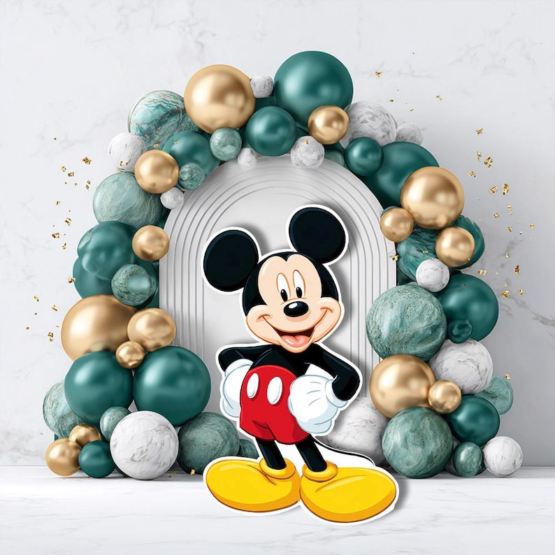 May include: A cheerful Mickey Mouse cutout stands before an arch of teal, gold, and marble-textured balloons. The iconic character is dressed in red shorts, yellow shoes, and white gloves, smiling brightly. The background features a white arch and gold confetti.