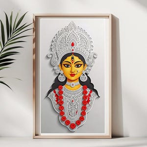 Puede incluir: Obra de arte enmarcada que presenta una detallada ilustración recortada en papel de una deidad con rostro amarillo, cabello negro y elaborado tocado blanco. Acentos florales rojos y blancos adornan el cuello y el pecho. La obra está enmarcada en un marco de madera clara.