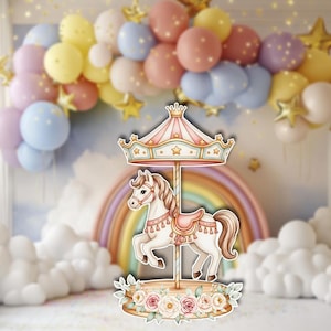 Könnte beinhalten: Karussell-Dekoration mit einem weißen Pferd, einem rosa Sattel und einem gestreiften Baldachin. Das Karussell ist mit Sternen und einer Krone verziert, vor dem Hintergrund von Ballons, einem Regenbogen und floralen Akzenten.