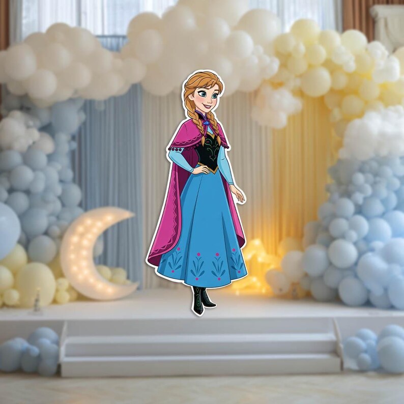 May include: A cutout of a cartoon character in a blue dress with a pink cape, standing on a white stage. The background features balloon arches in white, blue, and yellow, and a crescent moon decoration.