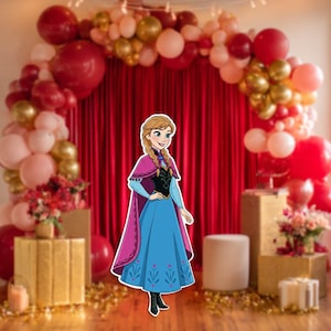 May include: A cutout of a cartoon character in a blue dress with a pink cape, standing in front of a red curtain and a balloon arch. The arch features red, gold, and pink balloons. Gold boxes and floral arrangements are on either side.