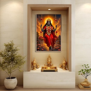 May include: A rectangular wall art print featuring a dark-skinned deity with long hair, wearing a red sari and a skull necklace, seated on a swing suspended over water with floating lotus flowers against a vibrant orange sunset background.