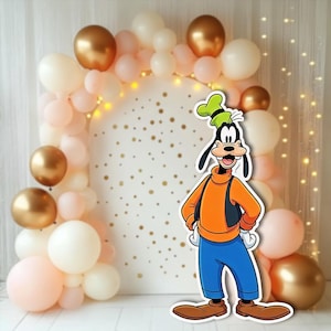 Puede incluir: Un telón de fondo de fiesta con un recorte de dibujos animados de Goofy frente a un arco blanco decorado con globos dorados, melocotón y blancos. El arco está salpicado de círculos dorados y rodeado de luces.