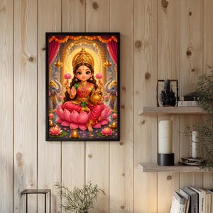 May include: A framed wall art print featuring a stylized illustration of a deity with large eyes, wearing gold jewelry and a red and green outfit, seated on a large pink lotus flower. Two elephants stand on either side amidst glowing oil lamps.
