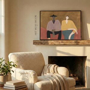 May include: A framed wall art print featuring a stylized illustration of two figures sitting side by side. The figure on the left wears a light purple top and black hat, while the figure on the right wears a yellow top and teal skirt.
