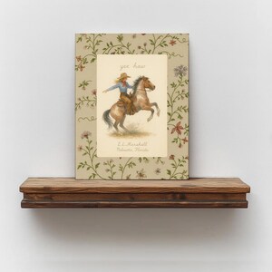 Puede incluir: Una impresi&oacute;n rectangular con una ilustraci&oacute;n central de una persona montando un caballo marr&oacute;n encabritado, con el texto yee haw y E.L. Marshall Palmetto, Florida. El borde muestra un fondo beige con un patr&oacute;n de enredaderas y flores.