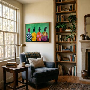 May include: An interior scene featuring a cozy armchair with a plaid blanket and a throw pillow. A wooden side table holds books and a mug. A framed artwork with figures in colorful patterns hangs above the chair. A tall bookshelf and a fireplace complete the room.