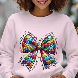 May include: A pink sweatshirt with a rainbow puzzle piece bow and the text "I would not change you. But I would change the world for you. But I would not change you. I would not change the world for you."