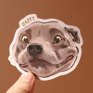 May include: A sticker featuring a cartoon dog with the word "HAPPY" above it. The dog has brown fur, a black nose, and a pink tongue sticking out.
