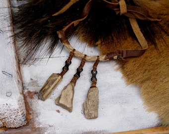 May include: A brown leather necklace with a rope and metal chain accents. The necklace has three wooden pendants hanging from it.