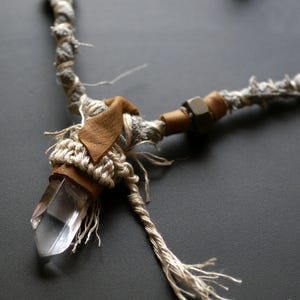 May include: A crystal point pendant necklace with a brown leather accent and a gray and brown rope chain.