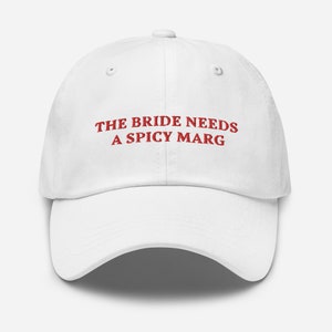 May include: White baseball cap with red embroidered text that reads "The Bride Needs a Spicy Marg".
