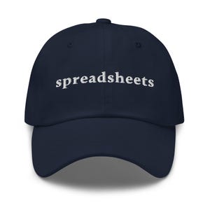 May include: A navy blue baseball cap with the word "spreadsheets" embroidered in white across the front. The cap has a curved brim and a button on top. This hat is a great accessory for anyone who loves spreadsheets.