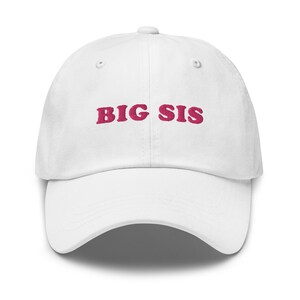 Puede incluir: Gorra de béisbol blanca con texto bordado en rosa que dice "BIG SIS".