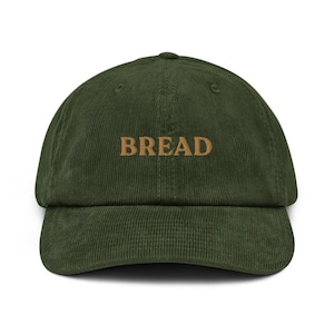 May include: A green corduroy baseball cap with the word "BREAD" embroidered in brown on the front.