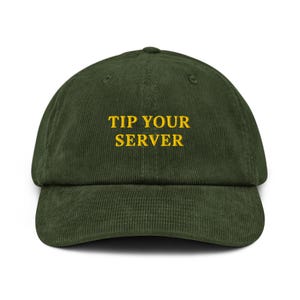 Könnte beinhalten: Dunkelgrüne Cord-Baseballkappe mit dem gelb gestickten Text "TIP YOUR SERVER". Die Kappe hat einen gebogenen Schirm und einen verstellbaren Riemen auf der Rückseite.