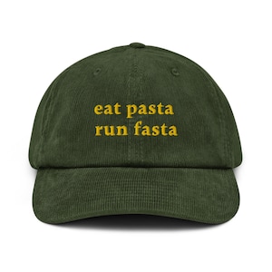 Peut inclure: Une casquette de baseball en velours côtelé vert avec le texte "eat pasta run fasta" brodé en jaune.