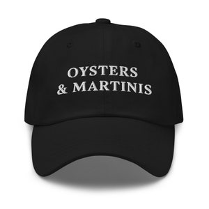 May include: Black baseball cap with white embroidered text that reads "Oysters & Martinis".
