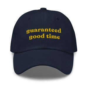 Puede incluir: Una gorra de béisbol azul marino con el texto "guaranteed good time" bordado en amarillo.