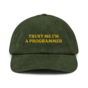 May include: A green corduroy baseball cap with the text "TRUST ME I'M A PROGRAMMER" embroidered in yellow.