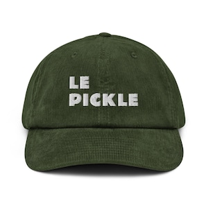 Könnte beinhalten: Dunkelgrüne Cord-Baseballkappe mit dem Text "LE PICKLE" in Weiß gestickt. Die Kappe hat einen gebogenen Schirm und eine strukturierte Krone. Der Hut ist ein lässiges Accessoire.