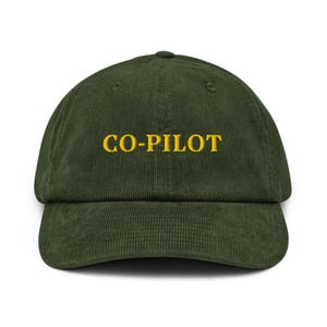 May include: A green corduroy baseball cap with the text "CO-PILOT" embroidered in yellow.