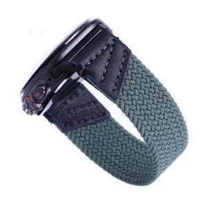 May include: A black smartwatch with a green braided strap. The strap has a black leather section with stitching. The watch face is black with a silver ring around it. The watch has a button on the side.