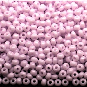 Peut inclure: Gros plan sur un tas de petites perles de rocaille rose clair. Les perles sont rondes avec un trou au centre et sont disposées de manière aléatoire. Ces perles sont idéales pour la création de bijoux et l'artisanat.