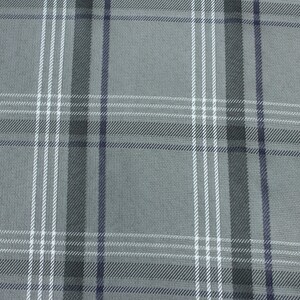Può includere: Primo piano di un tessuto a quadri grigio con un motivo ripetuto. Il motivo a quadri presenta strisce verticali e orizzontali in bianco, grigio scuro e blu navy. Il tessuto ha un aspetto strutturato.