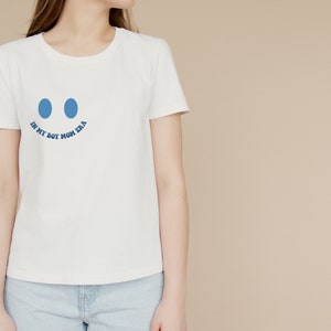 May include: White t-shirt with a blue smiley face graphic and the text "In My Boy Mom Era" printed on the front.