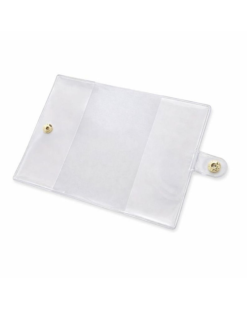 May include: A clear, rectangular wallet or card holder with a gold snap closure. The wallet is made of transparent plastic and has a simple, minimalist design. The interior has multiple compartments for organization.