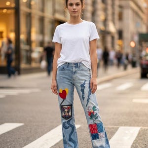 Puede incluir: Una camiseta blanca lisa de manga corta combinada con unos vaqueros de mezclilla azul claro con varios parches decorativos, incluyendo un corazón rojo, un diseño floral, un patrón de cuadros coloridos y un estampado gráfico.