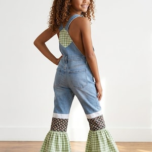 May include: Light blue denim overalls featuring a green and white gingham patch on the back bib, a white horizontal band above the knees, a black floral patterned section, and wide, flared green and white gingham ruffles at the leg hems.