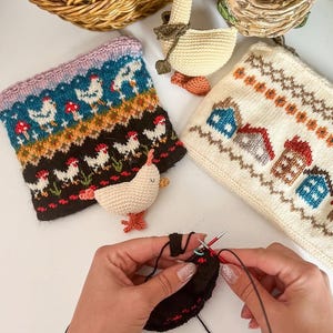 Puede incluir: Una colección de artículos de punto hechos a mano, que incluyen un brazalete con temática de gallinas, una bolsa con estampado de casas y un pato de ganchillo. La imagen también muestra a una persona tejiendo con hilo y agujas negras.