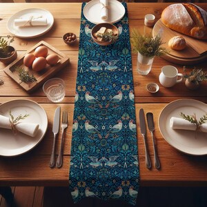 May include: A dining table set for a meal, featuring a blue patterned table runner with bird and floral motifs. The table is set with plates, silverware, and food items like bread and eggs. The overall color scheme is warm with natural wood tones.