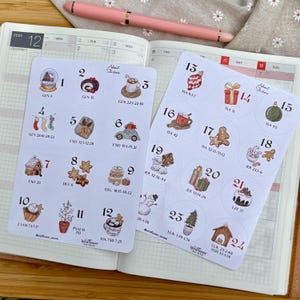 Op de afbeelding: Twee vellen adventsstickers met genummerde cirkels met feestelijke illustraties zoals een peperkoekmannetje, kerstboom en cadeaus. De stickers bevatten bijbelverzen en de tekst "Wildflower Soiree."