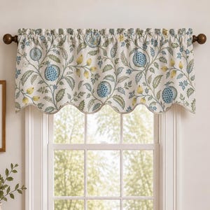 May include: A window valance featuring a botanical pattern of blue pomegranates, green leaves, and yellow buds on an off-white background. The fabric has a scalloped bottom edge and is suspended from a dark brown curtain rod with round finials.