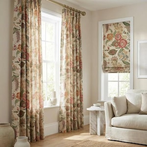 May include: A room with floral patterned curtains and a matching Roman shade. The curtains and shade feature a cream background with red, pink, and green floral designs. A beige sofa and a marble side table are also visible.