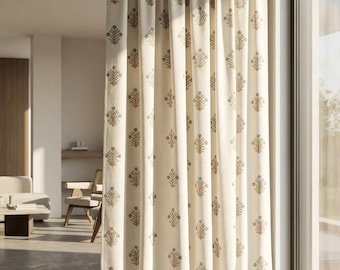 May include: A floor-length curtain panel in an off-white fabric featuring a repeating vertical pattern of small, stylized floral motifs in muted blue and tan tones. The curtain hangs in soft, vertical folds from a rod, covering a large window.