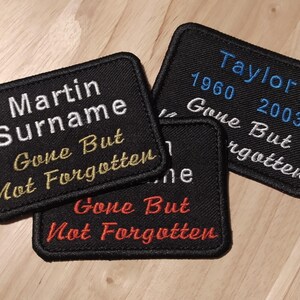 May include: Three black fabric patches with white and gold embroidery. The patches say "Gone But Not Forgotten" and include names and dates. The top patch says "Taylor 1960 2003". The middle patch says "Martin Surname". The bottom patch says "Gone But Not Forgotten".