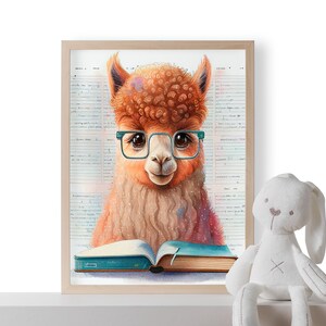 May include: A framed print featuring a whimsical illustration of an alpaca wearing glasses and reading a book. The alpaca has orange fur and is set against a background of handwritten notes. The book is open with blue pages. A white stuffed bunny sits nearby.