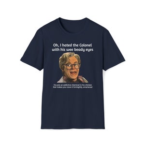 May include: A navy blue t-shirt with a white graphic of a man with glasses and the text "Oh, I hated the Colonel with his wee beady eyes. He puts an addictive chemical in his chicken that makes you crave it fortnightly, smartarse!"